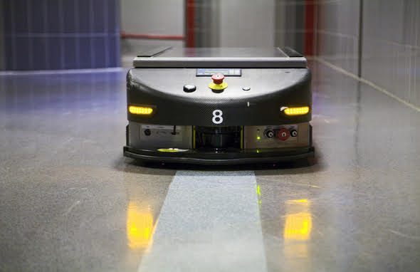 An AGV robot is autonomously navigating through a hallway in a building.