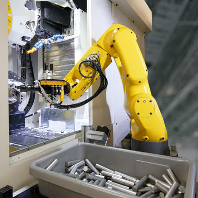 A yellow robot is tending to a machine.